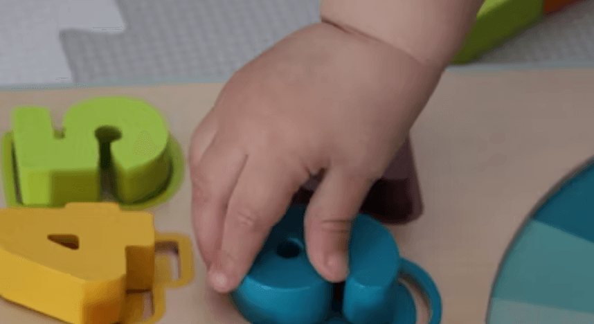 実際に型はめパズルに子供が手を伸ばしている様子