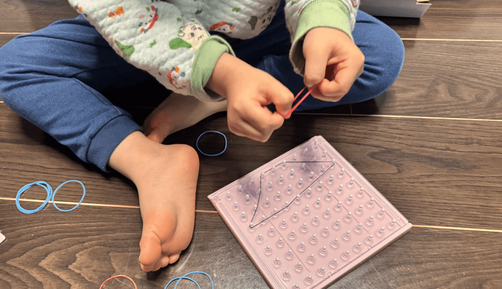 3歳の息子が輪ゴムおもちゃに輪ゴムをかけようとしている画像