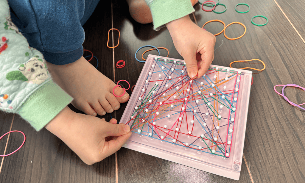 巧緻性が高くなってだんだん没頭してくもんのおもちゃに輪ゴムをかけている画像